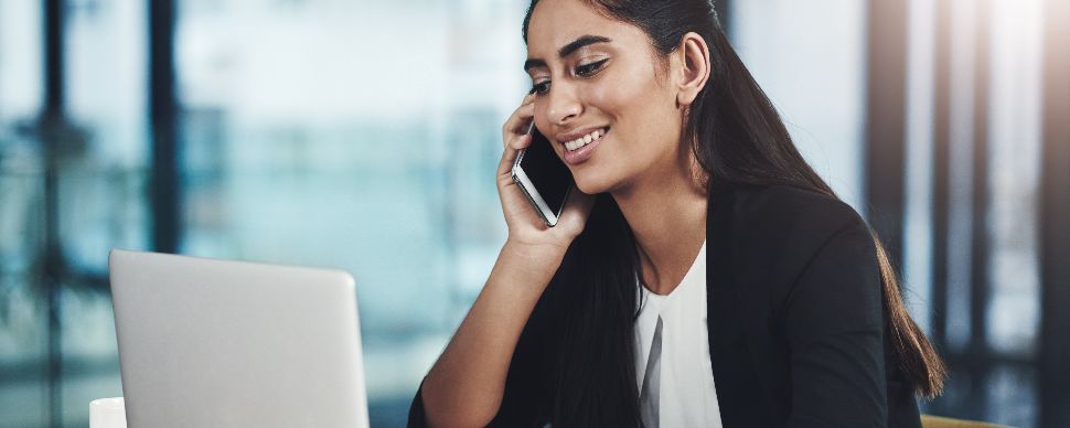 Woman-on-phone-Smiling-While-Using-a-Laptop