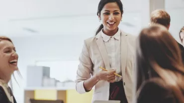 Smiling businesswoman leading a meeting with colleagues in an office.