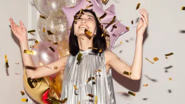 asian woman celebrating hands in the air, confetti