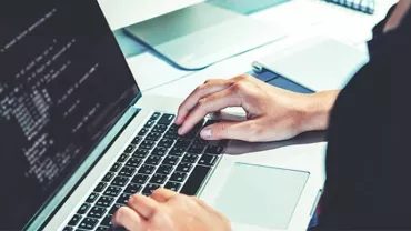 Person typing on a laptop with code on the screen.