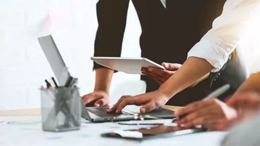 People collaborating with laptops and tablets around a table.