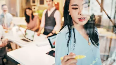 Woman writing on glass board during a meeting