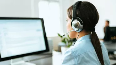 Person with a headset working at a desktop computer.