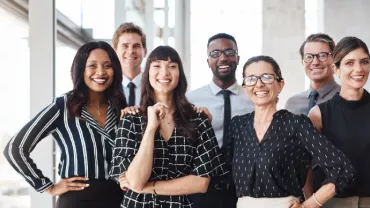 A diverse group of professionals smiling in an office setting.