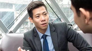 Two businessmen in discussion inside a modern office building.