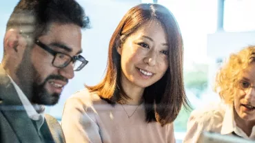 Three colleagues smiling and collaborating on a project