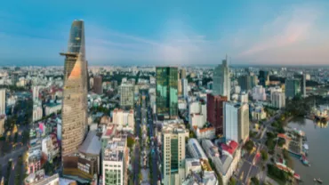 Panoramic view of a city skyline with modern high-rise buildings and a river at sunset.