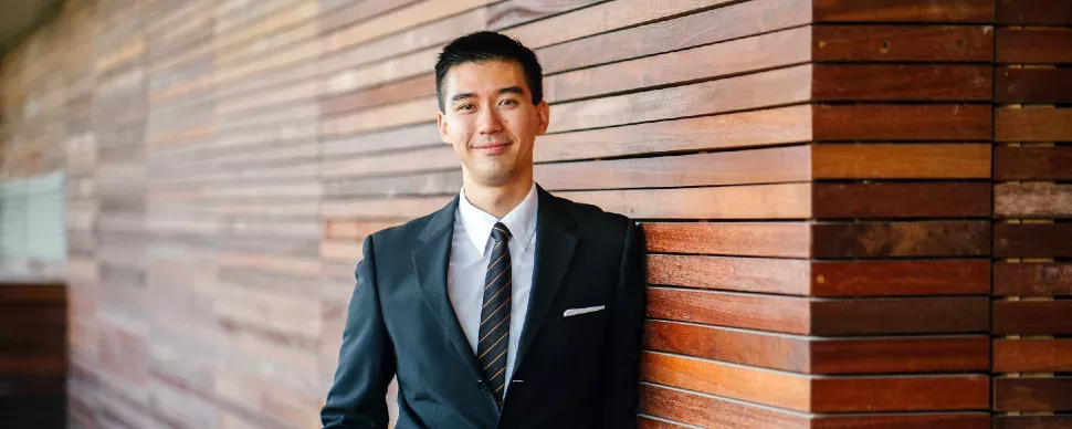 Man in suit leaning against wooden wall